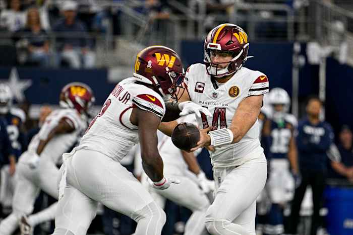 Washington Commanders running back Brian Robinson Jr. takes the handoff from quarterback Sam Howell.